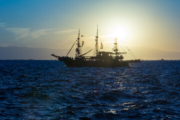 silhouette of a sailboat against the picturesque sunset and mountains