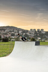 Giovane skater che esegue un trick all'aperto lo sfondo è una collina al tramonto sulla città di Koper.