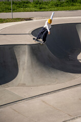 Giovane skater che esegue un trick all'aperto in una bowl di cemento, skate park cittadino