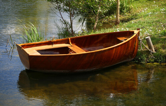 A small wooden row boat is tied to shore.