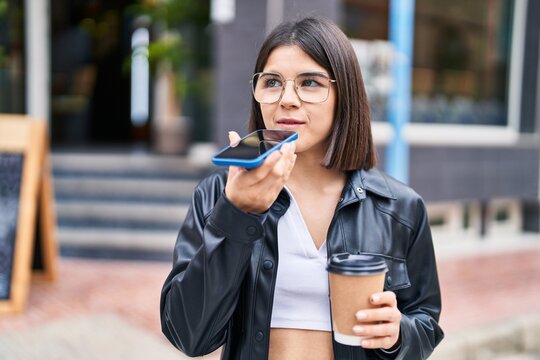 Young beautiful hispanic woman talking on the smartphone drinking coffee at street