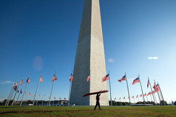 One man walking by a national memorial in nice light with a stand up paddleboard (SUP).