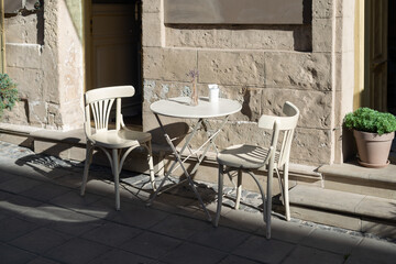 Lovely purple flowers on white rustic wooden outdoor furniture. Two chairs and table. street photo