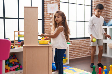 Brother and sister playing with play kitchen play and bowling at kindergarten