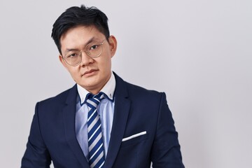 Young asian man wearing business suit and tie looking sleepy and tired, exhausted for fatigue and hangover, lazy eyes in the morning.