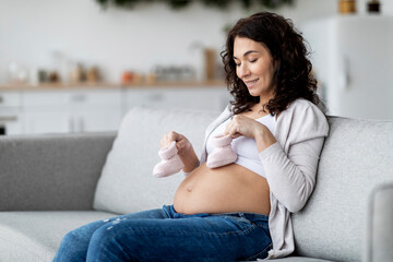 Beautiful Young Pregnant Woman Placing Small Baby Shoes At Her Belly