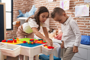 Brother and sister playing with construction blocks standing at kindergarten