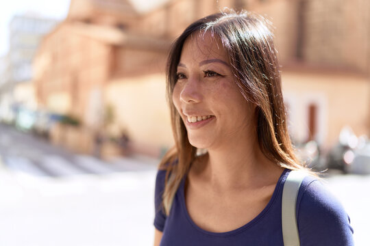 Young asian woman smiling confident looking to the side at street