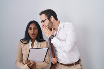 Interracial business couple wearing glasses hand on mouth telling secret rumor, whispering...
