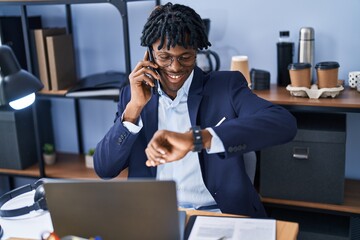 African american man business worker talking on the smartphone looking watch at office