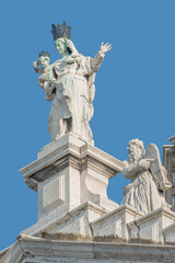 Fototapeta na wymiar Ancient sculpture of beautiful Venetian Noble Renaissance Era woman with child at Basilica di Santa Maria della Salute in Venice, Italy, at blue sky solid background