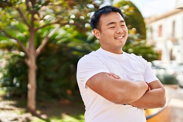 Young chinese man smiling confident standing with arms crossed gesture at park