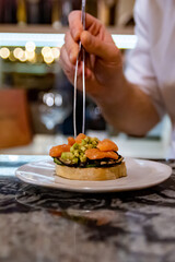 man chef hand cooking Bruschetta with avocado, mushroom and salted salmon