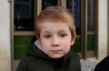 A blond boy with sad eyes. A thoughtful five-year-old boy. 