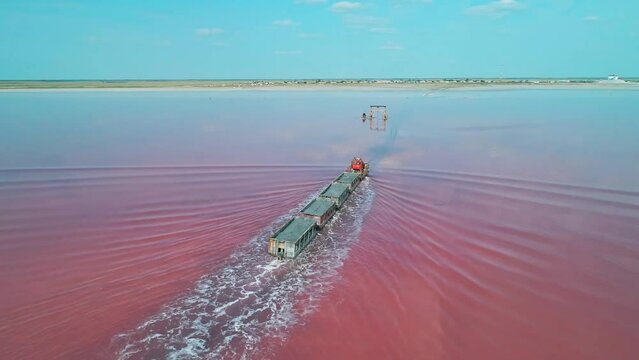Aerial view of an old train rides on the railway laid in the water through the salt lake. Salt mining in Lake Burlin. Altai. Bursol.