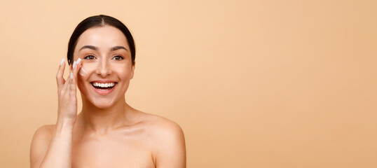 Beauty Banner. Attractive Young Indian Woman Applying Moisturizing Cream On Face