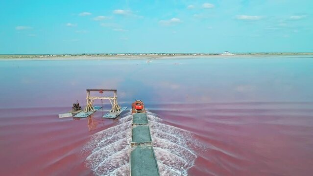 Aerial view of an old train rides on the railway laid in the water through the salt lake. Salt mining in Lake Burlin. Altai. Bursol.