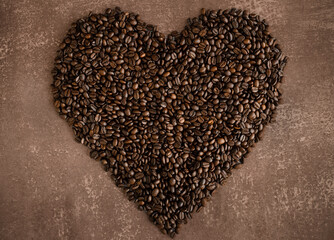 Herz aus gerösteten Kaffeebohnen auf hellbraunem melierten Hintergrund, horizontal 