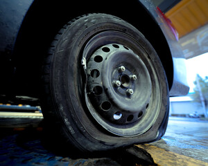 Car with a punctured and broken wheel in a car repair shop