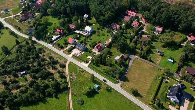 Mountain village and road with moving cars, aerial view. Beautiful mountain landscape with residential neighborhood and green fields. Countryside view