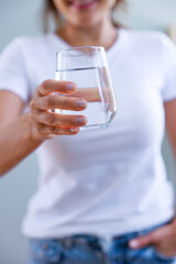 Young woman showing a full glass of water in her hand