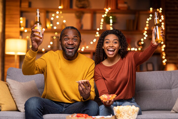 Emotional black couple spending evening together at home, watching game