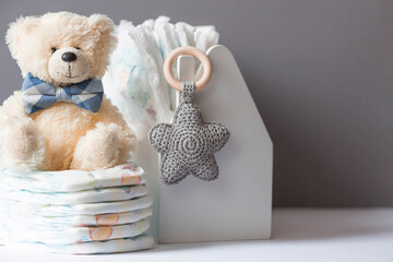 Wooden toys, a bear in a bow tie, a stack of diapers and baby supplies on the changing table. Space...