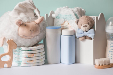 Wooden toys, a bear in a bow tie, a stack of diapers, bottles without labels and baby supplies on...