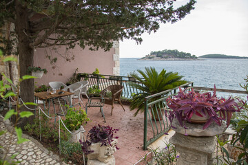 Beautiful sea view terrace decorated with flowers, green tropical plants and garden furniture along...