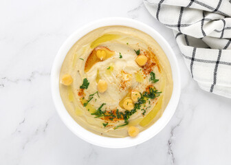 Classic hummus with chickpeas, parsley and olive oil in a bowl on a white background. Top view. Arabic, Turkish cuisine.