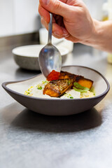 chef hand cooking grilled salmon fish fillet with creamy ptitim, cheese and caviar