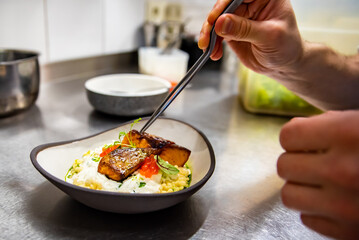 chef hand cooking grilled salmon fish fillet with creamy ptitim, cheese and caviar