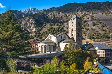 Fototapeta na wymiar Beautiful, 11th century stone St. Esteve Church surrounded by green trees with Pyrenees Mountains in background, Andorra la Vella