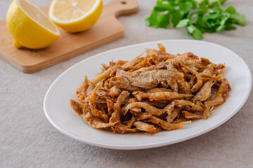 Crispy fried small fish on white plate