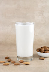 A glass of almond milk and almond kernels on a beige background. Copy Space. Selective focus. Concept of lactose free nutrition.