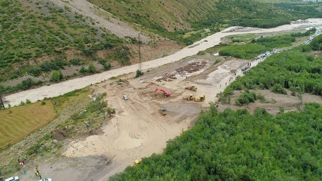 Aerial of an excavator and wheeled bulldozers removing massive mudflow from the roadway. Natural disaster.