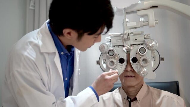 Ophthalmologist doing eye test on male patient in an exam room. male optician or optometrist specialist checking vision of a Senior man using examination equipment inside an optometry clinic