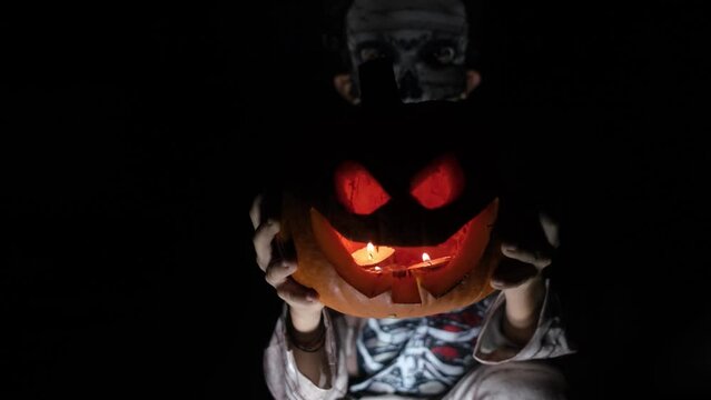Boy dressed as mummy with illuminated halloween pumpkin with bela at night terror trick or treat hallowen autumn celebration