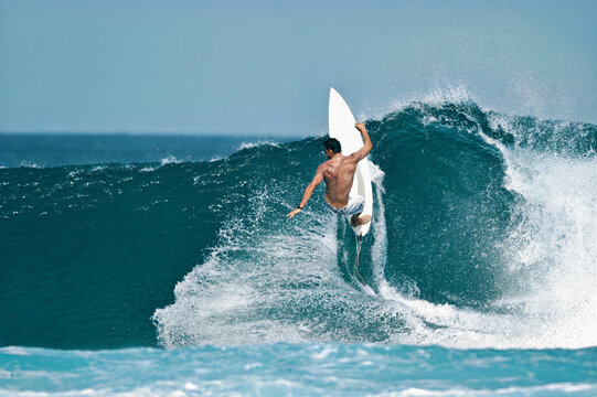 A surfer carves a radical off-the-lip on a beautiful blue wave in the ocean.	