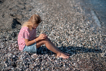 Little beautiful smiling girl lying on the sand at the beach.