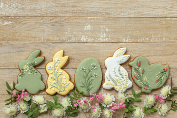 wooden background with easter icing cookies and flowers