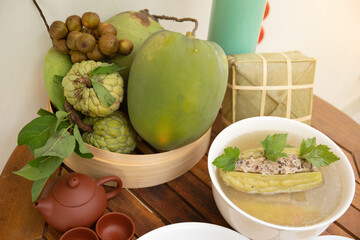 Family dinning table of Tet holiday or Lunar New Year with traditional foods: pork belly and eggs braised in coconut water, pickles, rice, Banh Tet (rice cake), fried vegetables, bitter melon soup