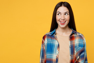 Young amazed surprised cheerful fun caucasian woman wearing blue shirt beige t-shirt look aside on workspace area mock up isolated on plain yellow background studio portrait. People lifestyle concept.