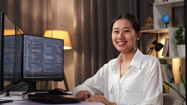 Asian Woman Programmer Smiling To Camera While Creating Software Engineer Developing App, Program, Video Game On Desktop Computer At Home. Terminal With Coding Language 
