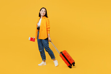 Young woman wear summer clothes hold passport ticket suitcase bag look aside isolated on plain yellow background. Tourist travel abroad in free spare time rest getaway Air flight trip journey concept