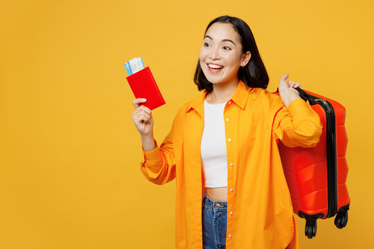 Sideways young woman wear summer casual clothes hold passport ticket suitcase isolated on plain yellow background Tourist travel abroad in free spare time rest getaway Air flight trip journey concept