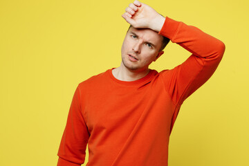 Young sad sick ill tired caucasian man wearing orange casual clothes put hand on forehead suffering from headache isolated on plain yellow color background studio portrait. People lifestyle concept.