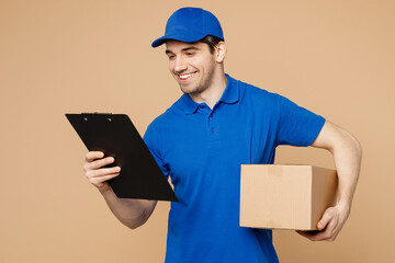Delivery guy employee man wearing blue cap t-shirt uniform workwear work as dealer courier hold clipboard with papers document cardboard box isolated on plain light beige background. Service concept. - obrazy, fototapety, plakaty