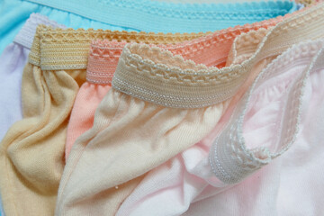 Several plain women's maxi cotton adult panties of mix colors with lace trimmings on the waistband of the undergarment, giving them a soft, feminine look. A set of lady's intimate wear. Closeup view.