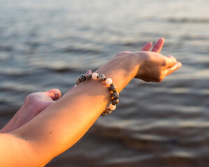a bracelet made of stones on a woman's hand against the background of sea water.